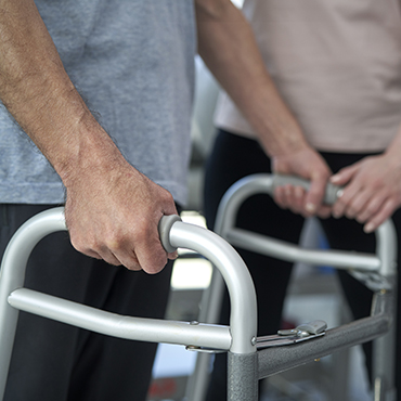 Close-up of a senior man's hands gripping a walker, demonstrating support for mobility assistance.